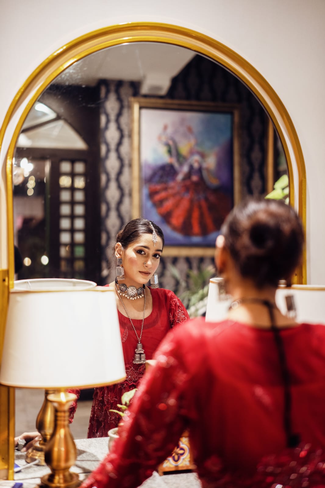 Observing herself in the mirror, she elegantly arranges the jewelry.