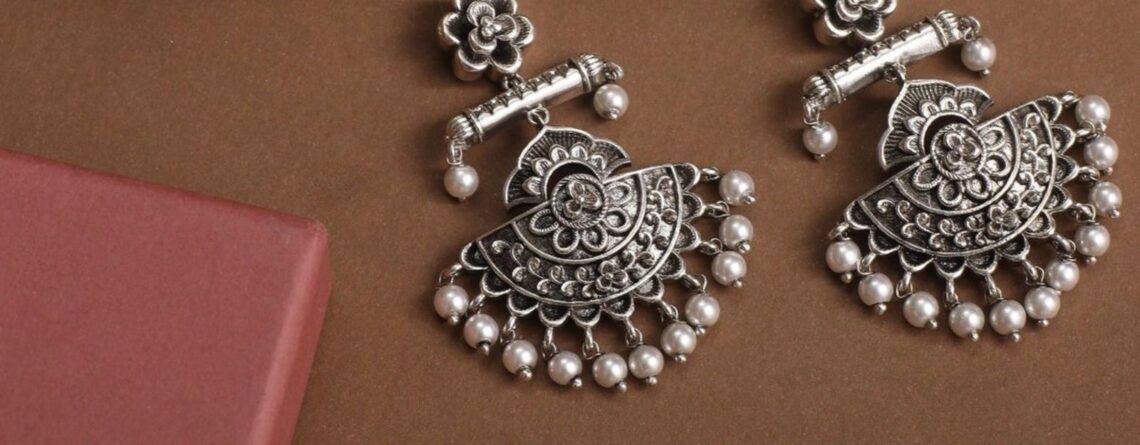 An art of a silver based earing on a brown background .