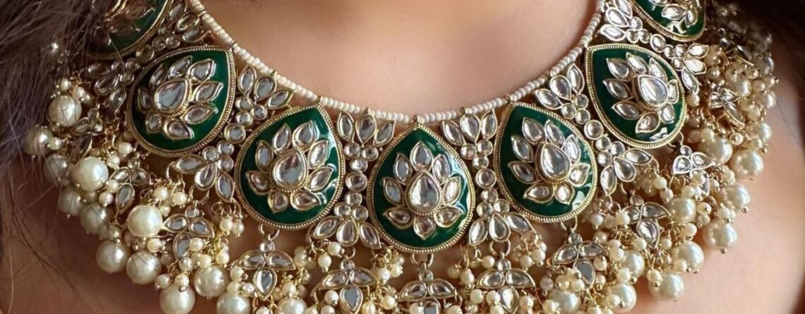 An emrald set with white pearls and mirror stone work on them, worn by a woman portraying the sophisticated art of fine quality artficial jewelry.