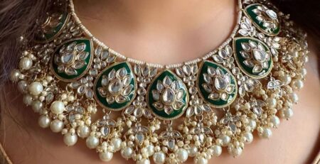 An emrald set with white pearls and mirror stone work on them, worn by a woman portraying the sophisticated art of fine quality artficial jewelry.