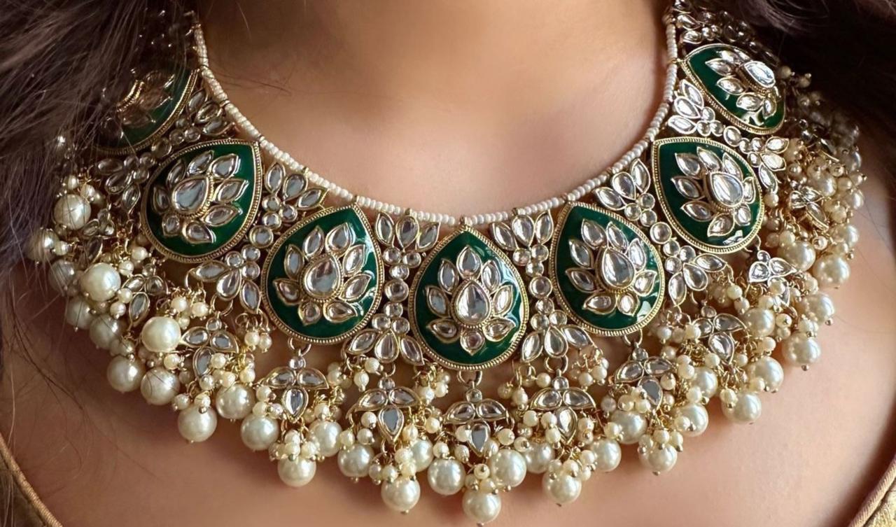 An emrald set with white pearls and mirror stone work on them, worn by a woman portraying the sophisticated art of fine quality artficial jewelry.